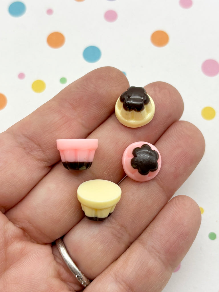 A hand holding four small, colorful plastic objects against a background with polka dots.
