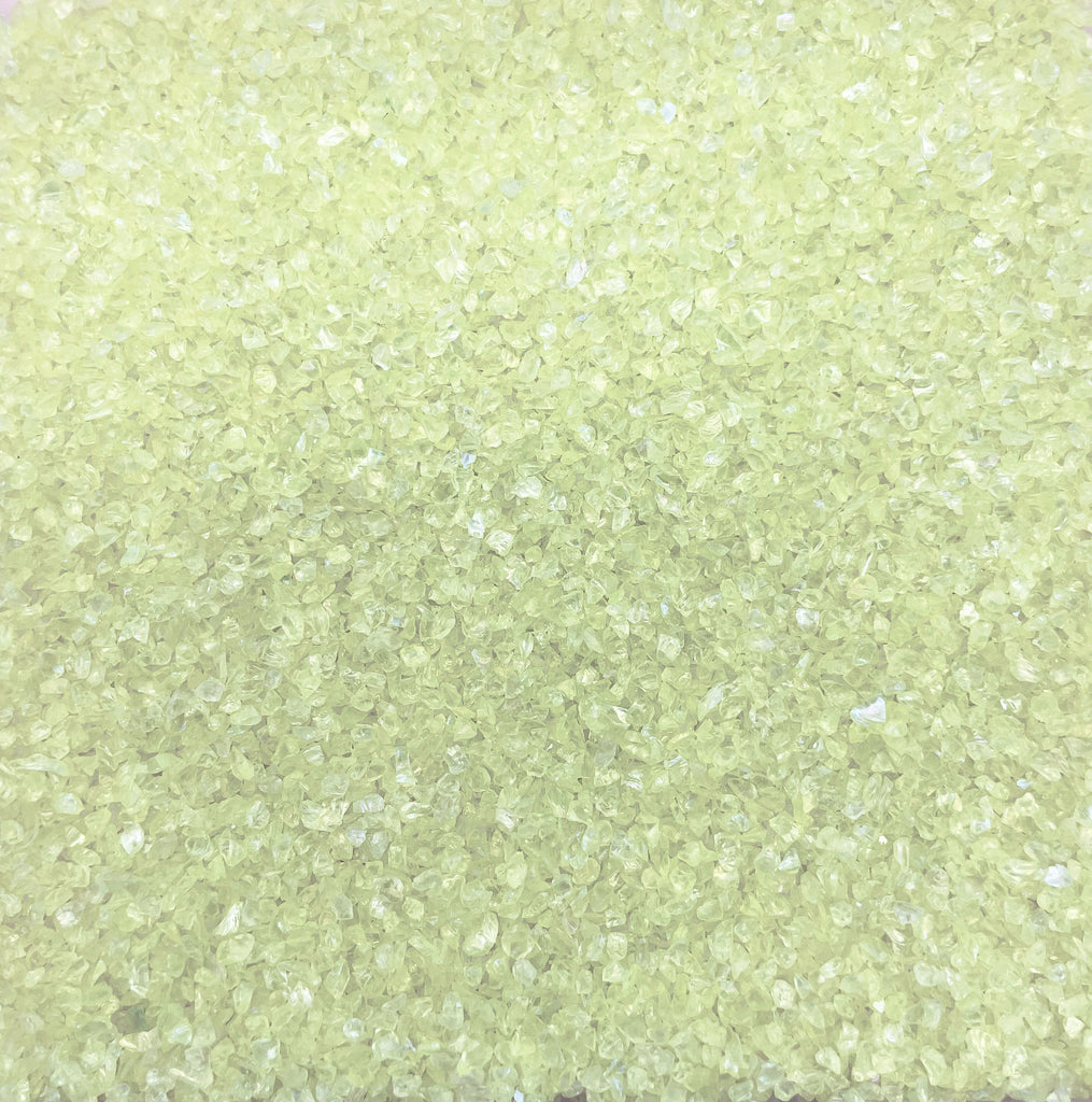 The image is a close-up of a surface covered with small, clear, yellow-green crystals or grains, creating a textured and visually interesting pattern.