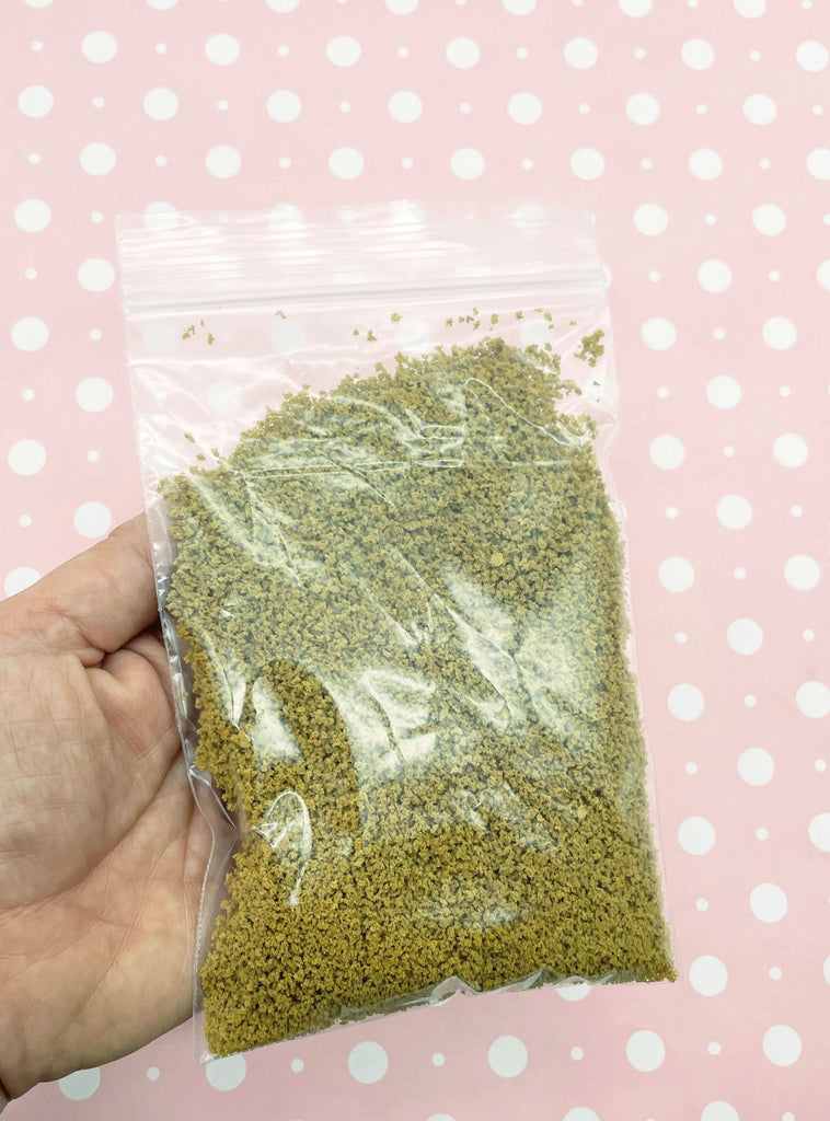 a hand holding a bag of green sprinkles