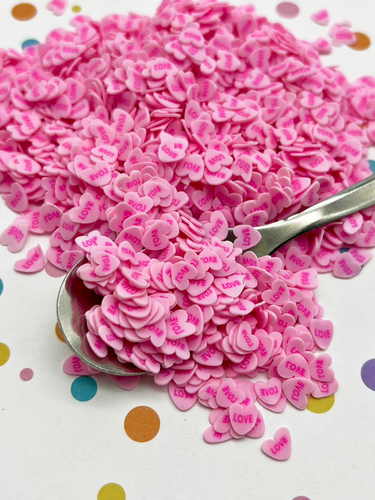 a spoon full of pink confetti sitting on a table