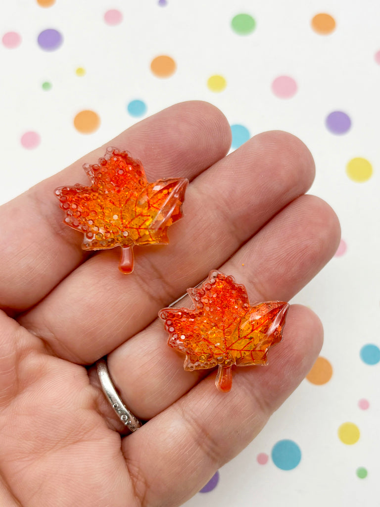 A hand holding two small, colorful leaf-shaped objects against a background with polka dots.