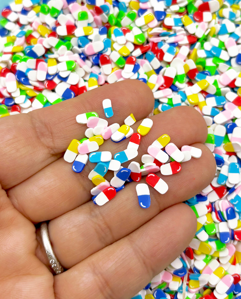 a hand holding a handful of colorful pills