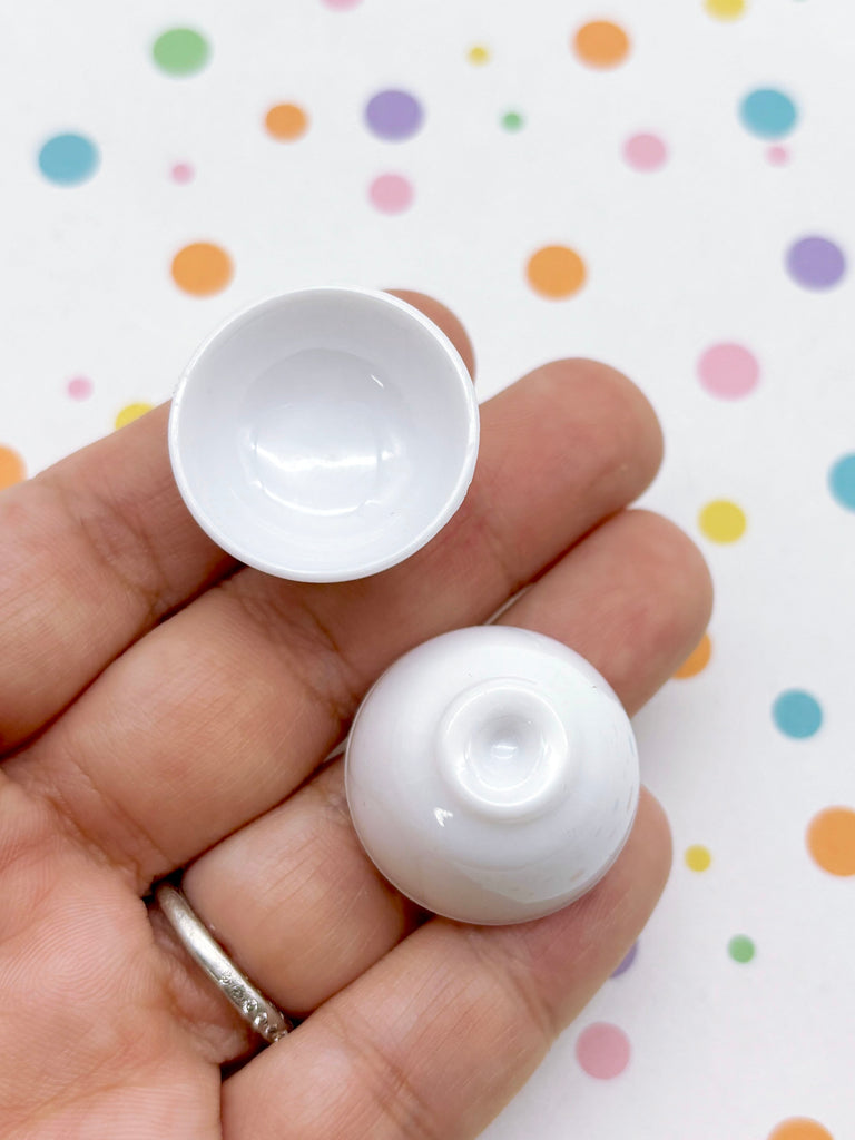 A hand holding two small white bowls against a background with colorful polka dots.