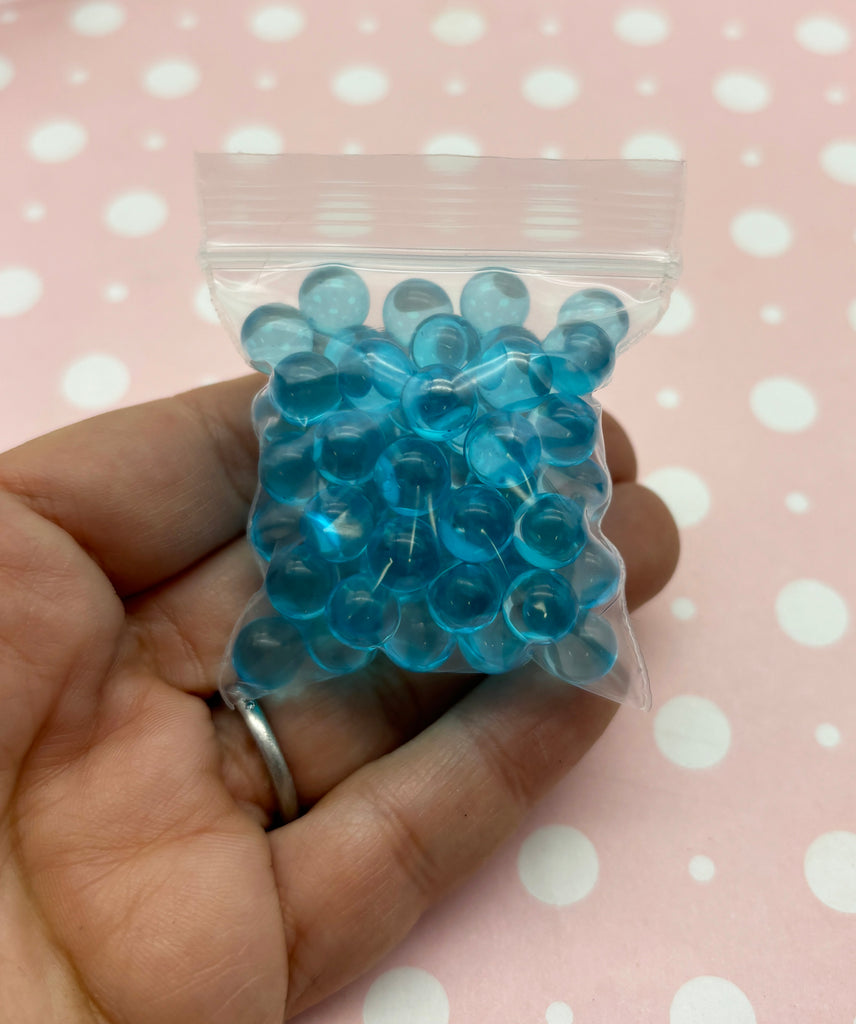 a hand holding a bag of blue beads