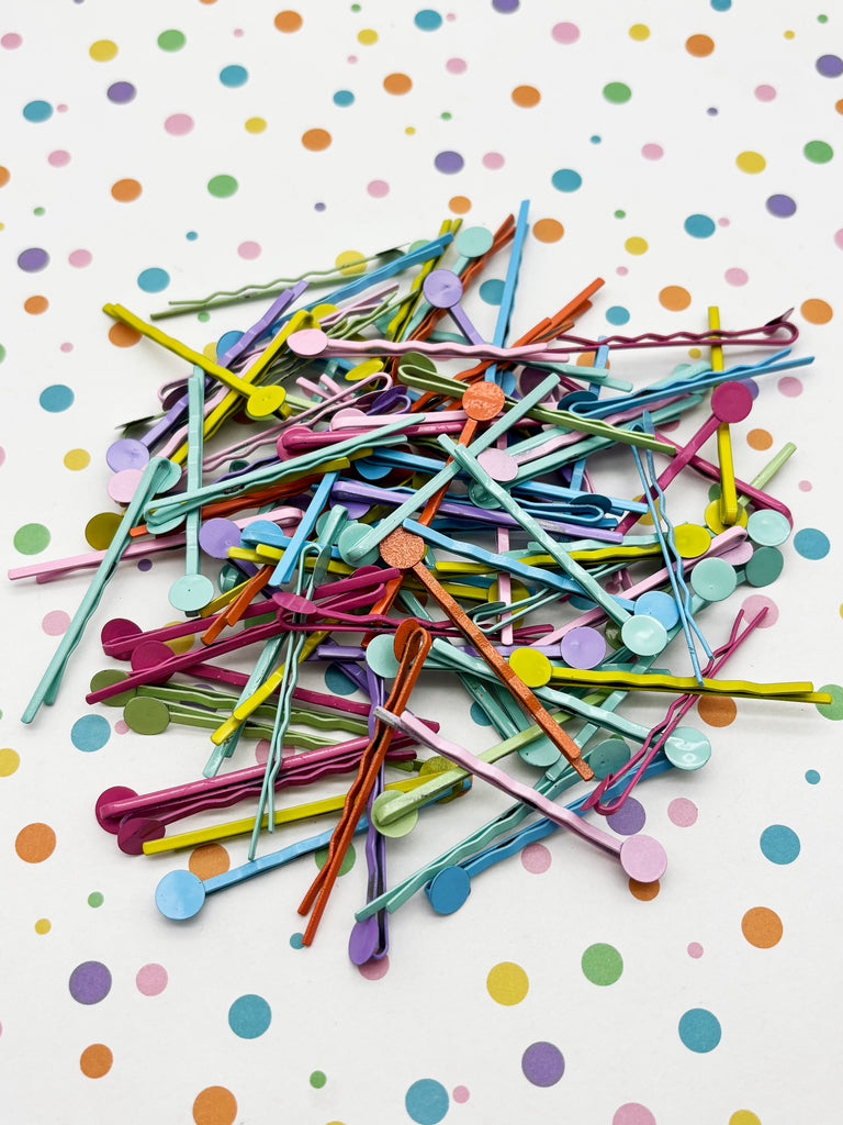 A pile of colorful plastic clips and bobby pins scattered on a white background with polka dots.