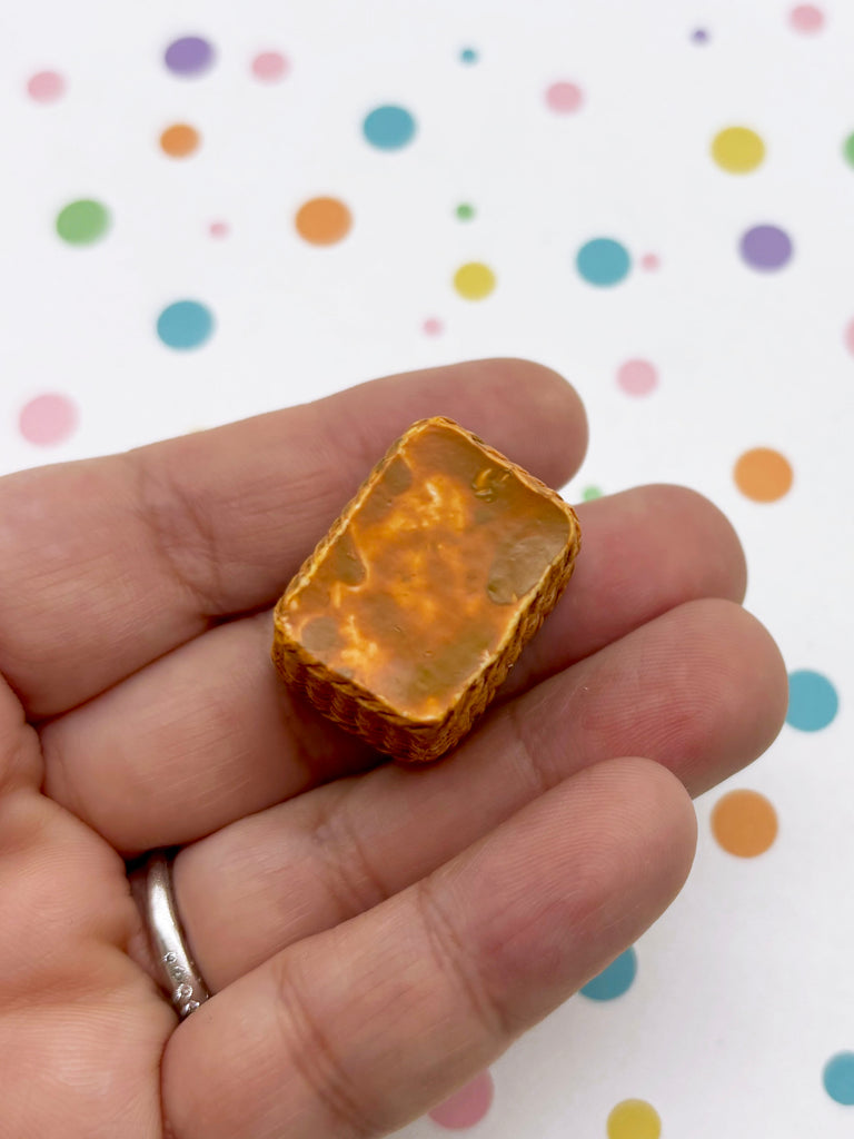 A hand holding a small, rectangular object against a background with colorful polka dots.