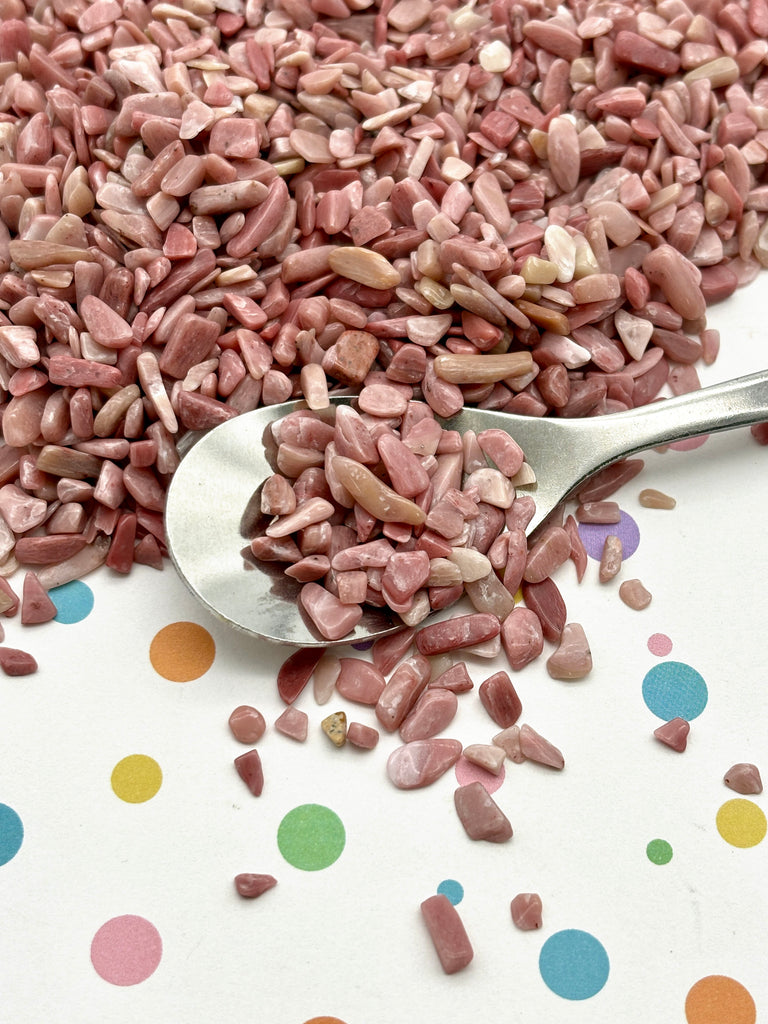 a spoon full of pink gravel sitting on top of a table