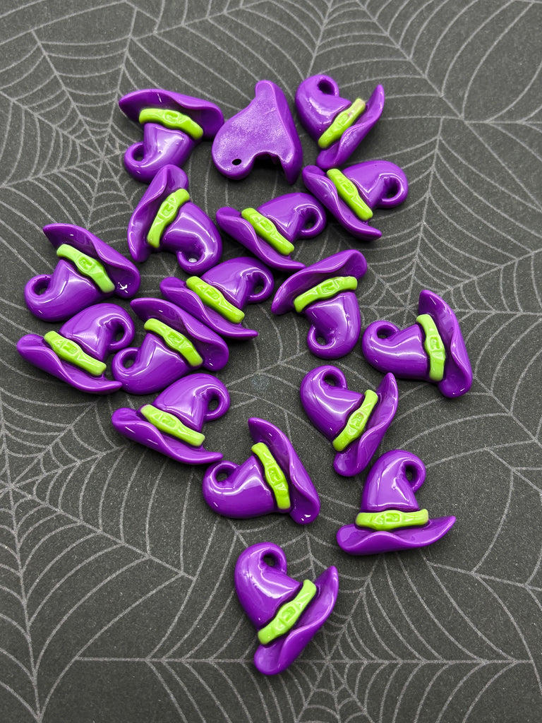 a collection of purple and green witch hats arranged on a gray background with a spider web pattern.