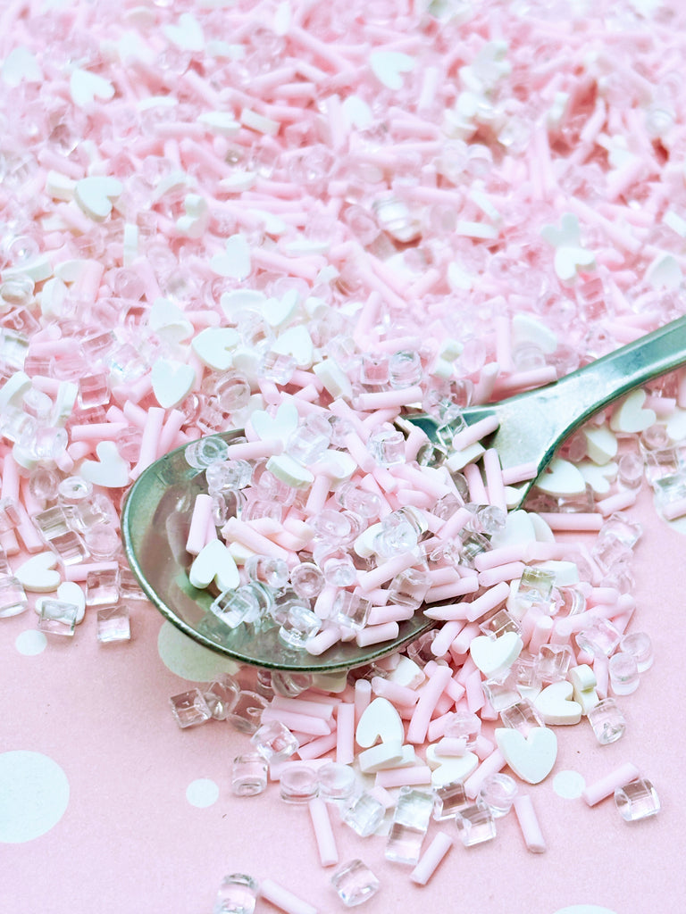 a spoon full of pink and white sprinkles