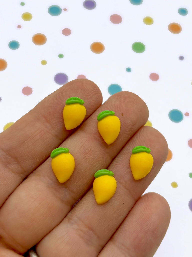 a hand holding a yellow and green pair of fruit earrings