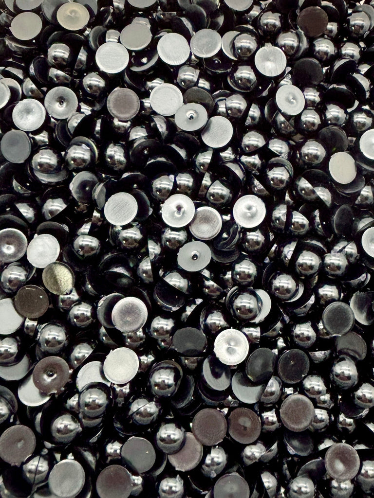 The image is a close-up of numerous small, shiny metal balls in various shades of black and silver, creating a visually striking and intricate pattern.
