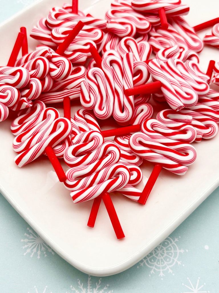 a white plate filled with red and white striped candy canes, arranged in a visually appealing manner.
