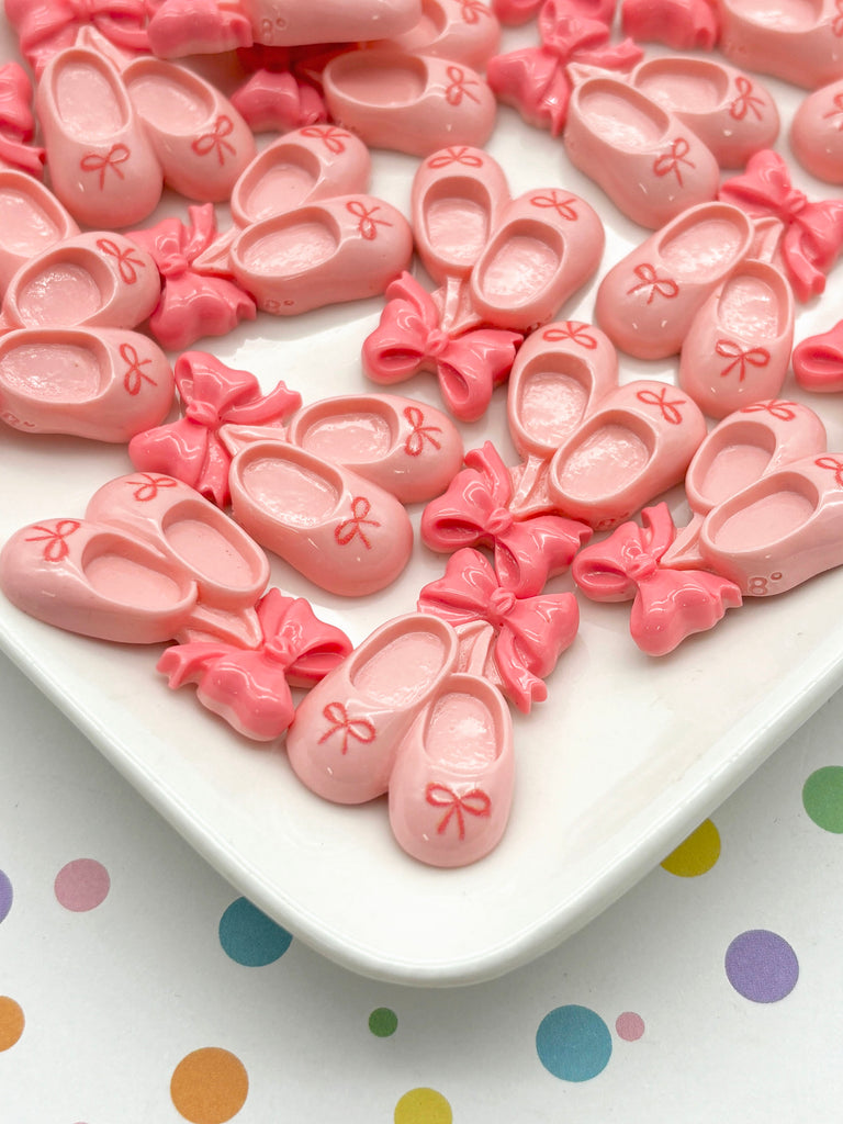 a white plate topped with lots of pink baby shoes