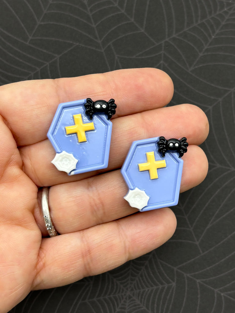 a pair of earrings with bows and a cross on them