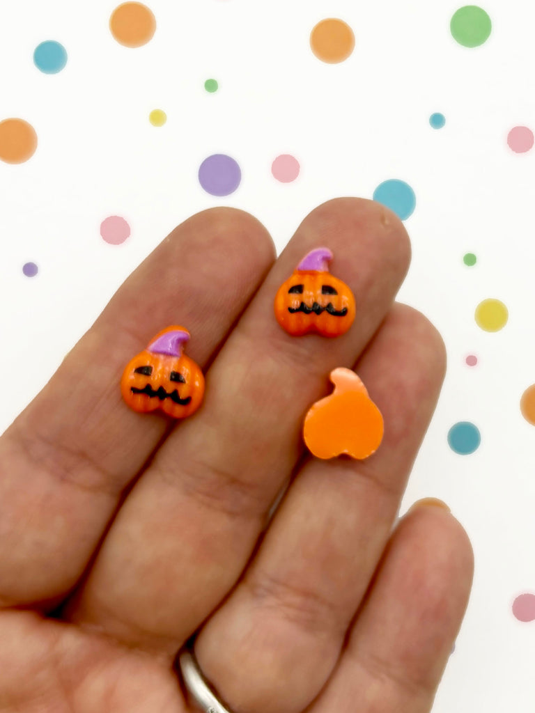 a hand holding a pair of fake halloween pumpkins