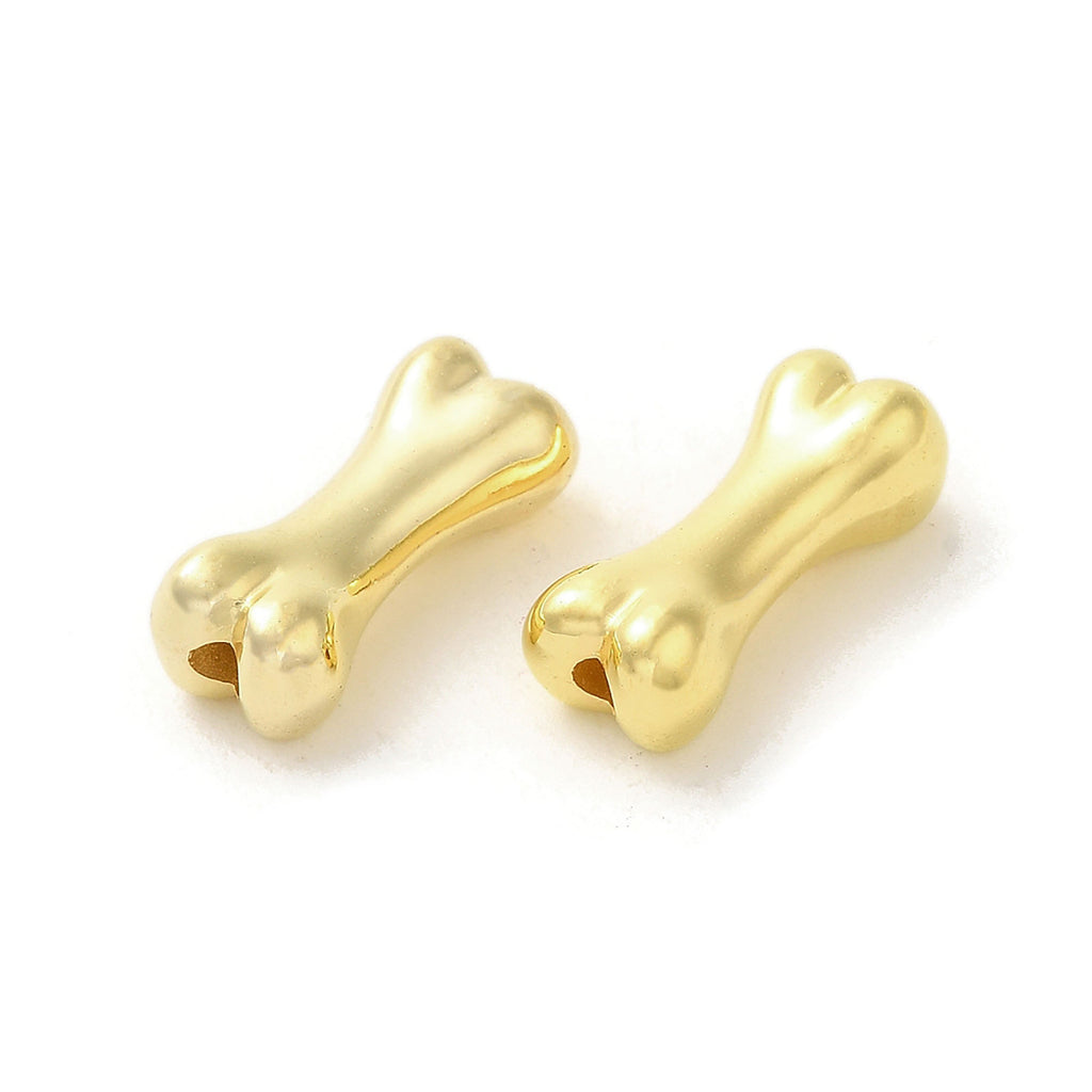 Two gold-colored metal bone-shaped charms are shown against a white background.