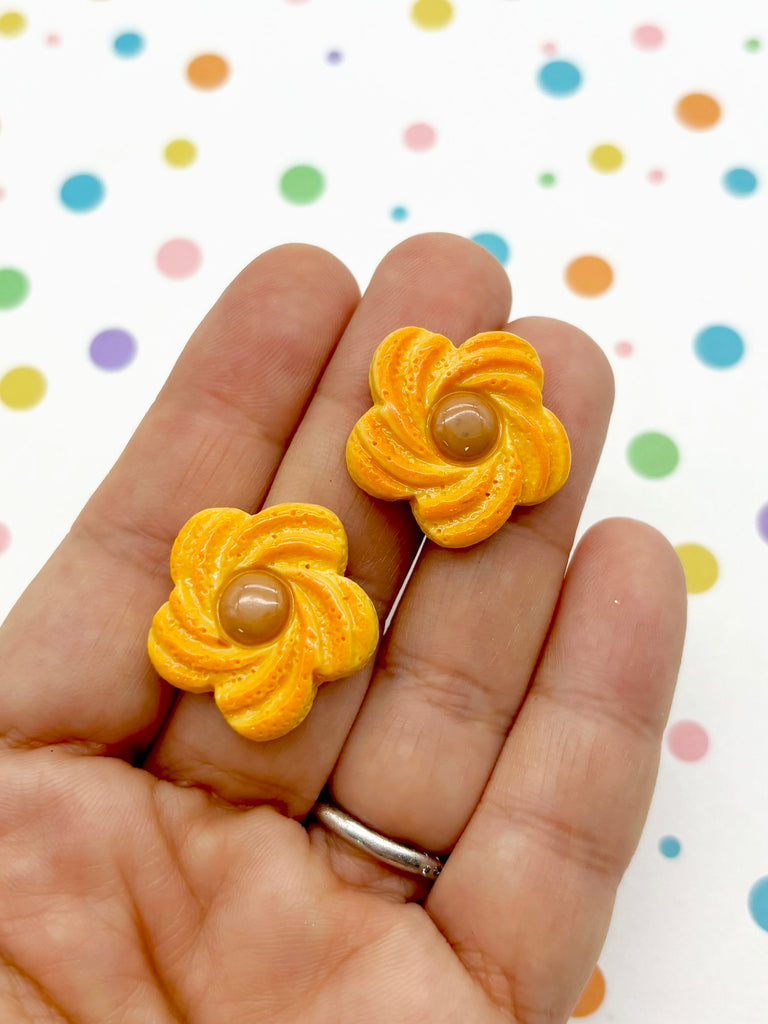 a hand holding a pair of yellow flower earrings