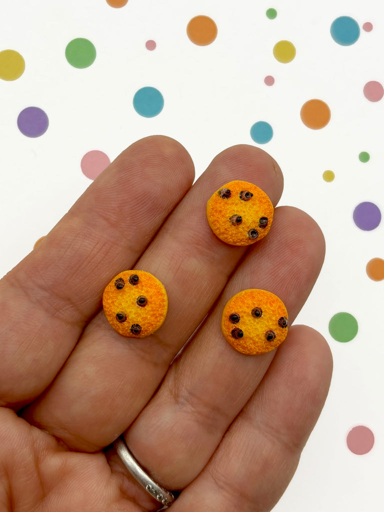 a hand holding a pair of tiny orange cookies