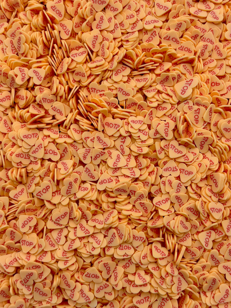 The image is a close-up of numerous small orange heart-shaped objects scattered across the frame.