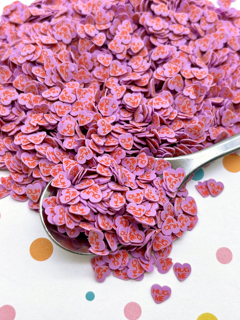 a spoon full of purple hearts sitting on a polka dot tablecloth