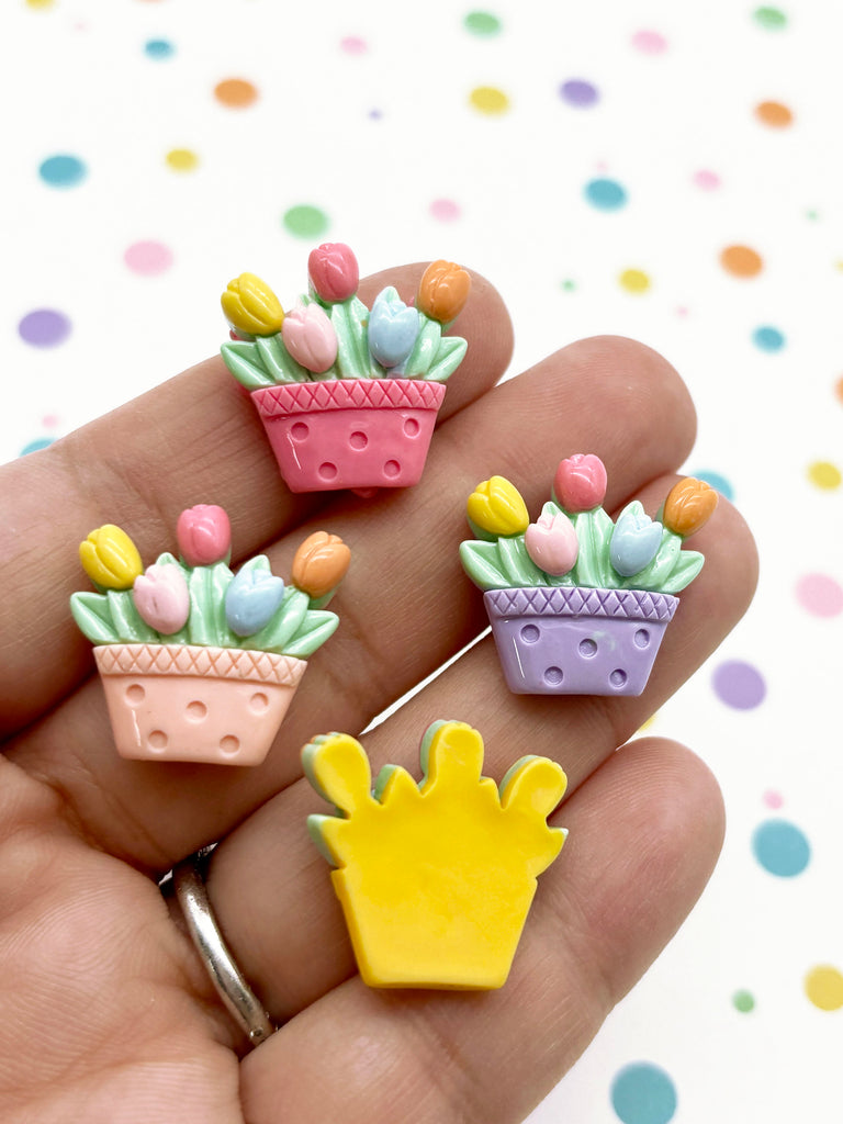a hand holding three small plastic flower pots