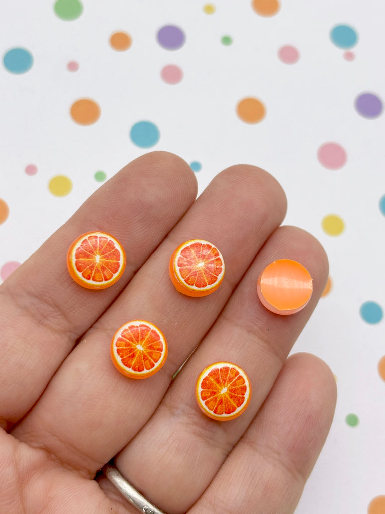 A hand holding five small orange fruit-shaped objects, with one of them being a larger orange fruit-shaped object.