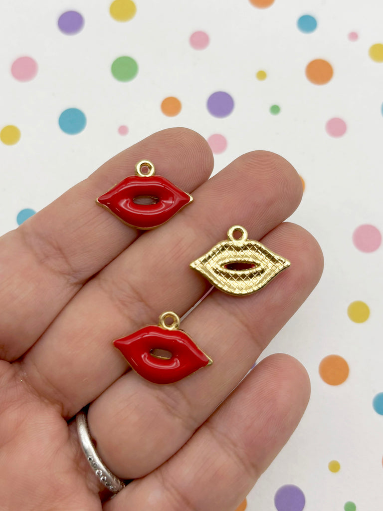 A hand holding three small charms in the shape of red lips against a background with colorful polka dots.