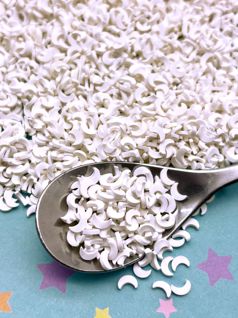 a spoon filled with white sugar sprinkles on top of a table