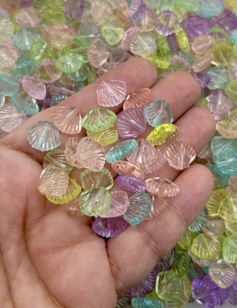 A hand holding a collection of multicolored glass beads, including various shades of pink, green, blue, and yellow.