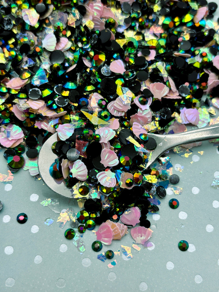 a spoon full of glitter next to a pile of confetti