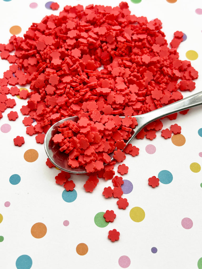 a spoon full of red confetti on top of a table