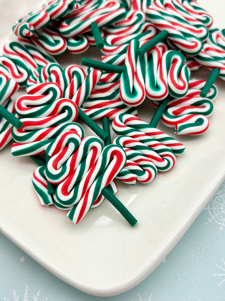a white plate filled with colorful candy canes, featuring red, green, and white stripes.