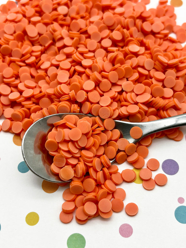 a spoon full of orange pills on a polka dot tablecloth