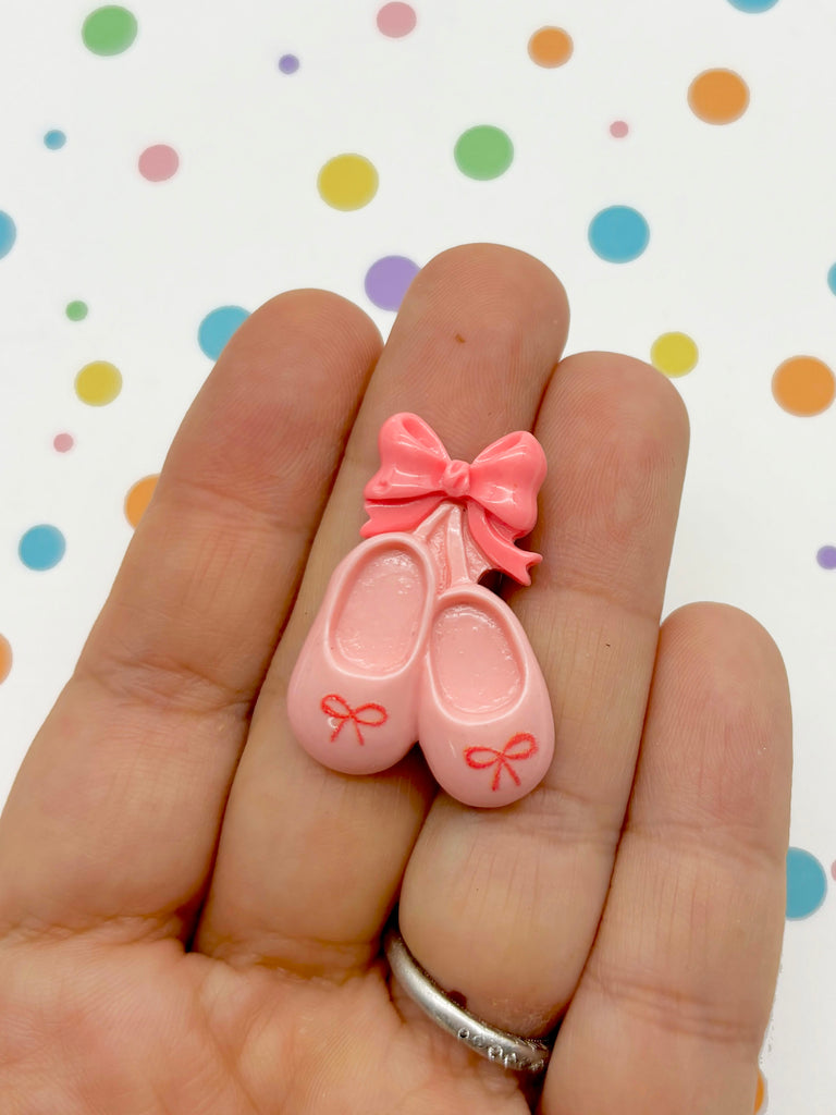 a hand holding a tiny pink pair of shoes