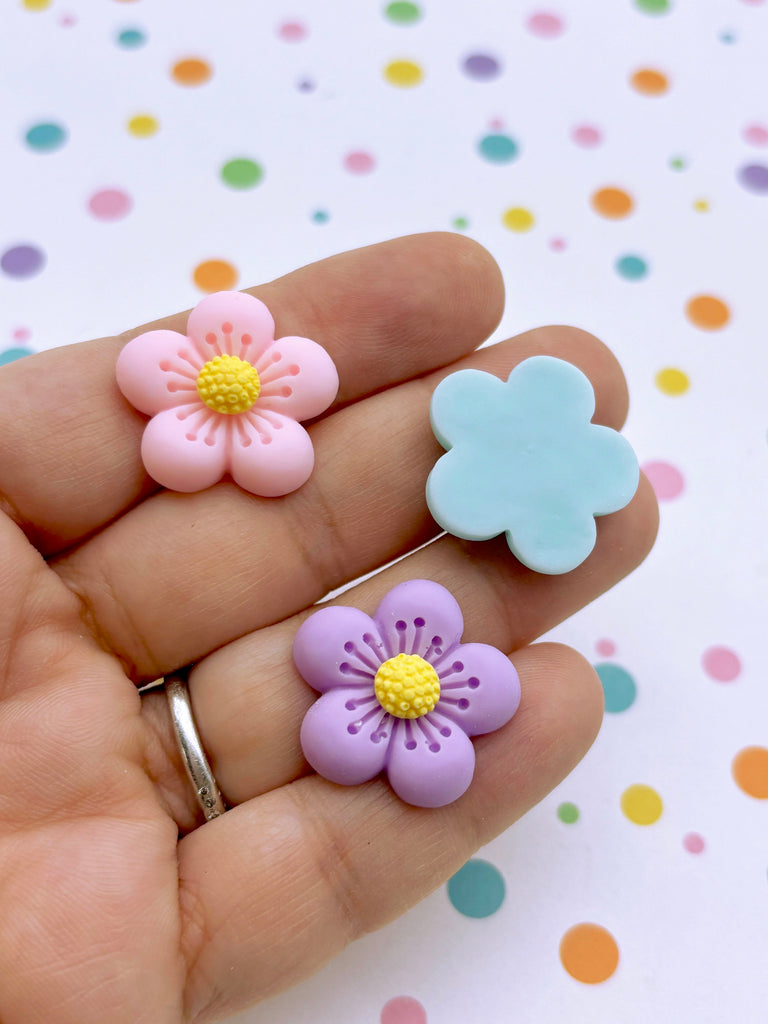 a person holding three small flowers in their hand