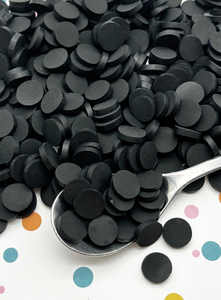a spoon full of black confetti on a polka dot tablecloth