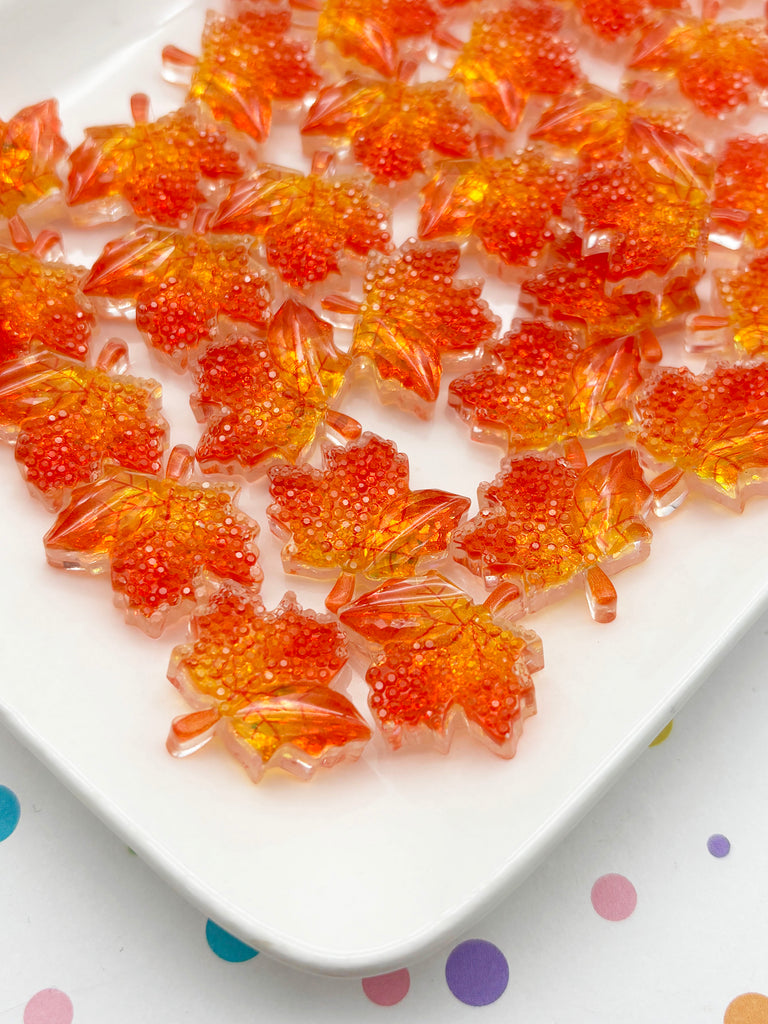 a white plate with numerous small, colorful, and shiny leaf-shaped candies arranged on it.