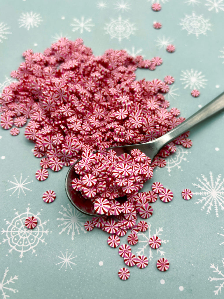 a spoon full of pink sprinkles on a table
