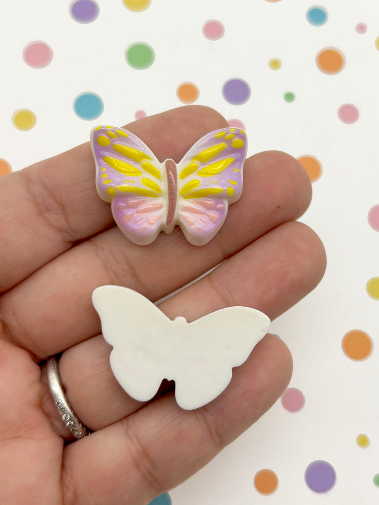 A hand holding a white butterfly-shaped object against a background with colorful polka dots.