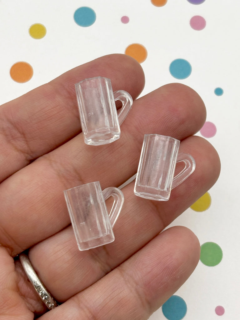 A hand holding three small, clear plastic cups against a background with colorful polka dots.