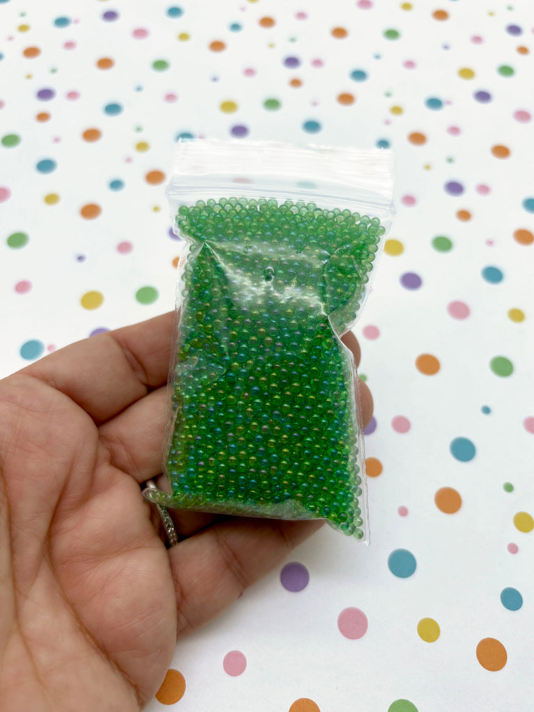 a hand holding a bag of green beads