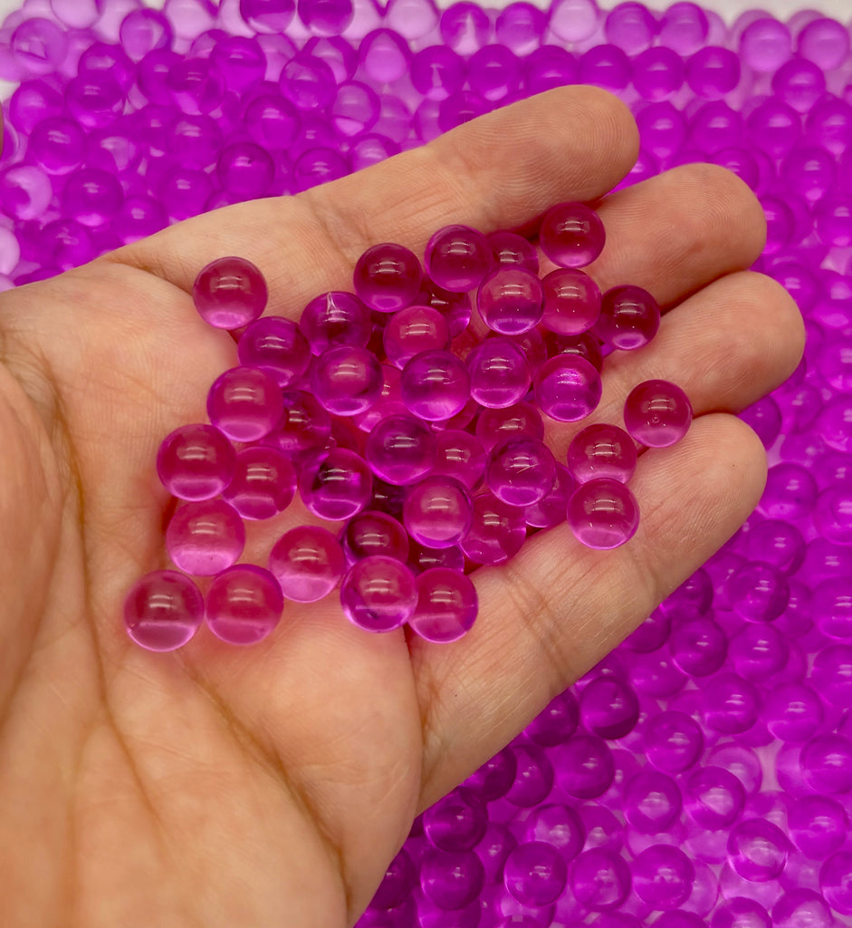 a hand holding a handful of purple beads