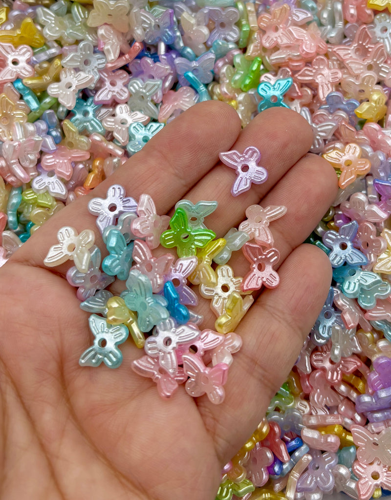 A hand holding a pile of multicolored, small beads in various pastel shades, including pink, blue, green, and yellow.