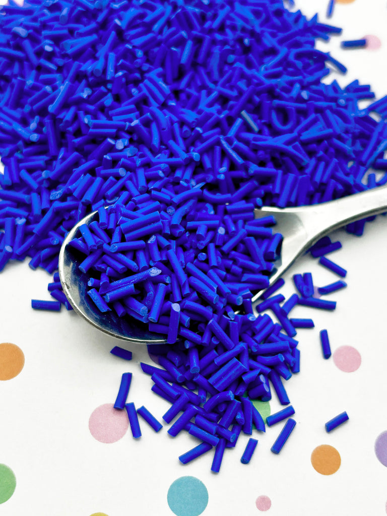 a spoon filled with blue sprinkles on top of a table