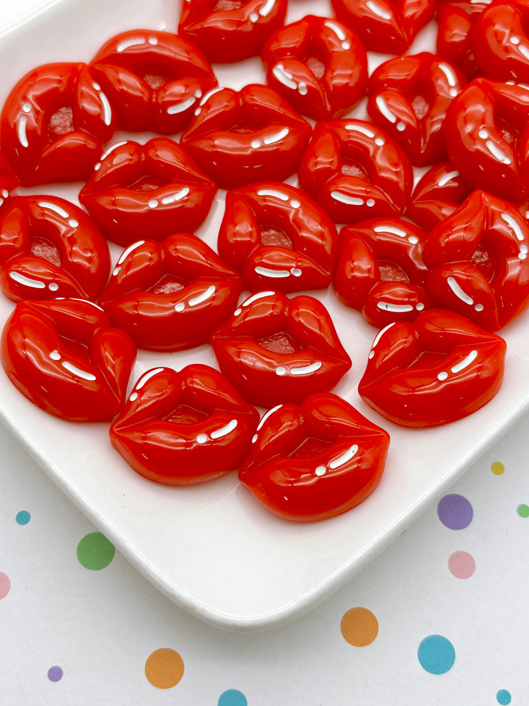 a white plate with a collection of red, shiny, and glossy candies arranged in a visually appealing manner.