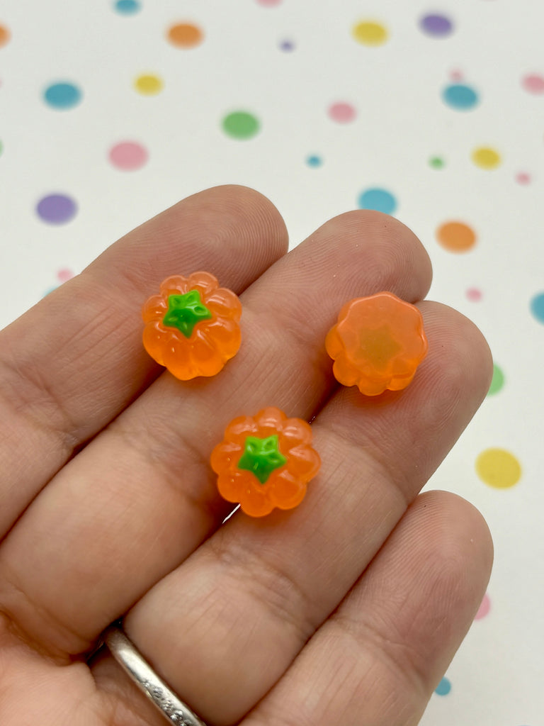 a hand holding three small orange flowers