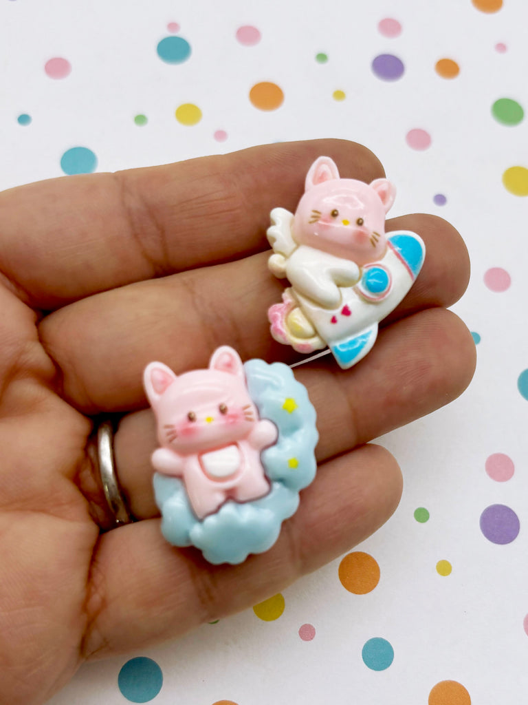 A hand holding two small, colorful figurines, one resembling a cat and the other a rocket ship, against a background with multicolored polka dots.