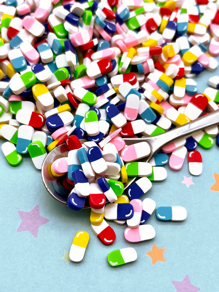 a spoon full of colorful pills on top of a table