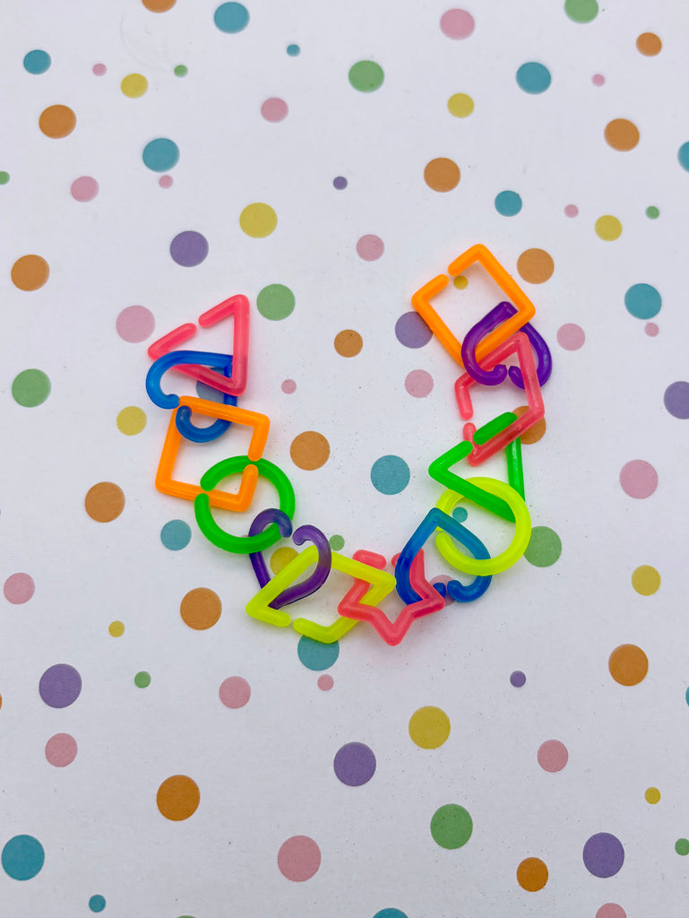 A colorful arrangement of various shapes and objects, including a heart-shaped piece, a triangle, and a star, against a background of multicolored polka dots.