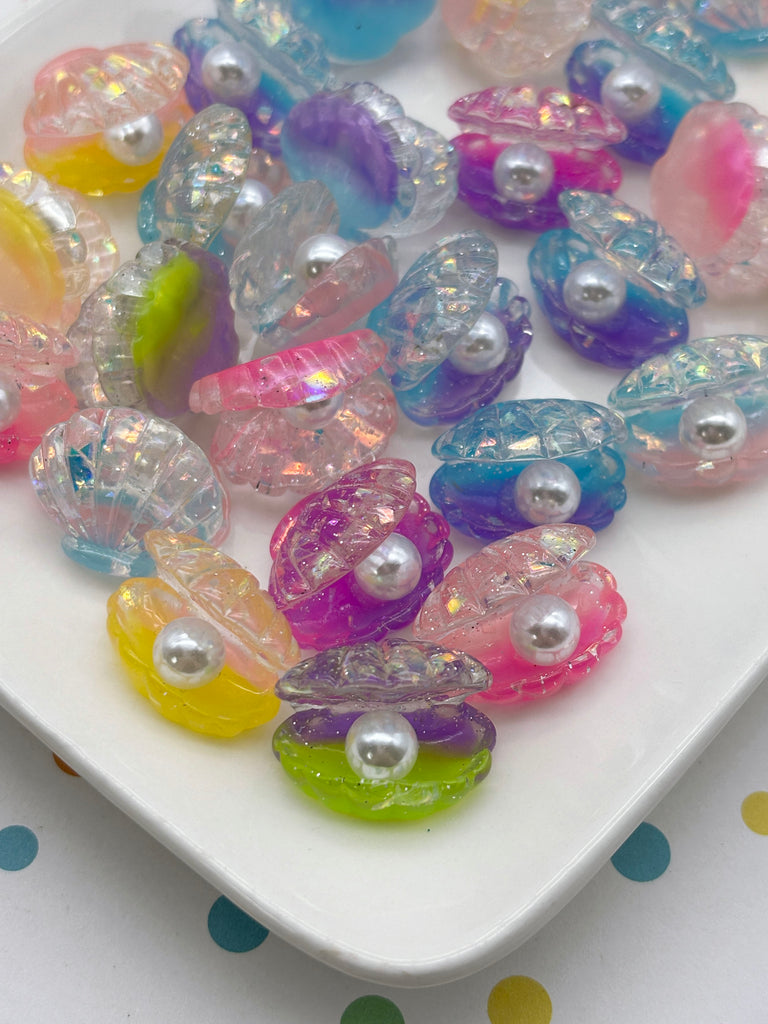 A white plate filled with colorful, glittery, and shiny seashell-shaped objects, including pearls and beads, arranged in a visually appealing manner.
